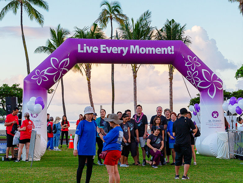 People standing underneath a printed freestanding inflatable race arch