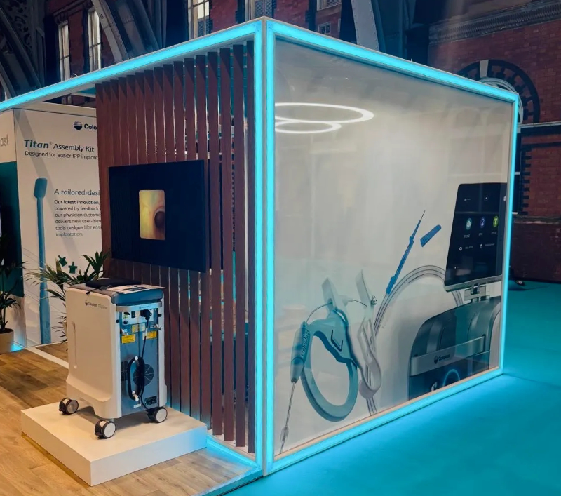 Close-up of Coloplast’s SEG fabric wall featuring medical product visuals, housed in a backlit modular frame with slatted feature wall and integrated AV screen.